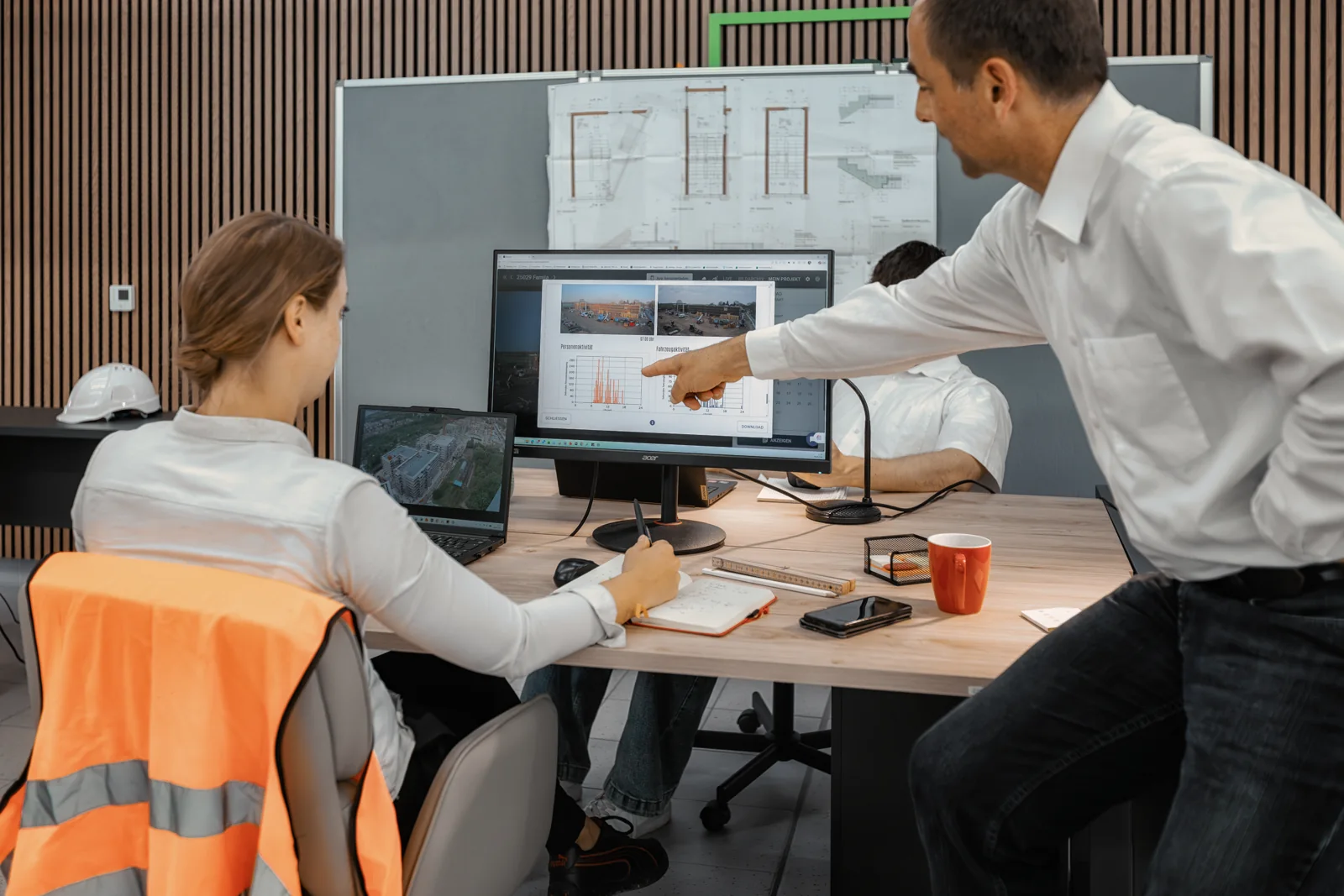 Site manager showing construction progress in the BauTV+ portal on a monitor