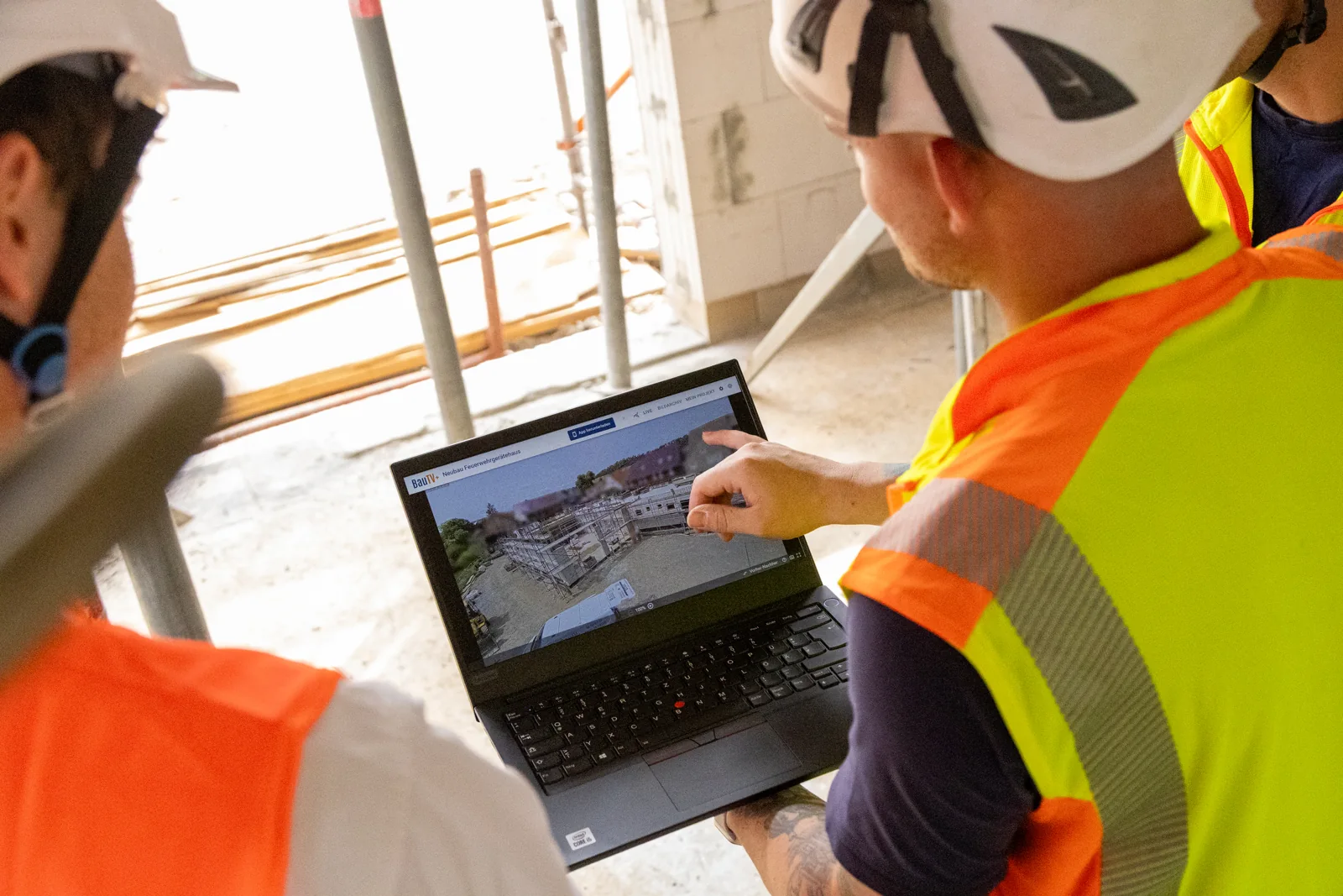 Foreman checking site documentation on a laptop inside the shell construction