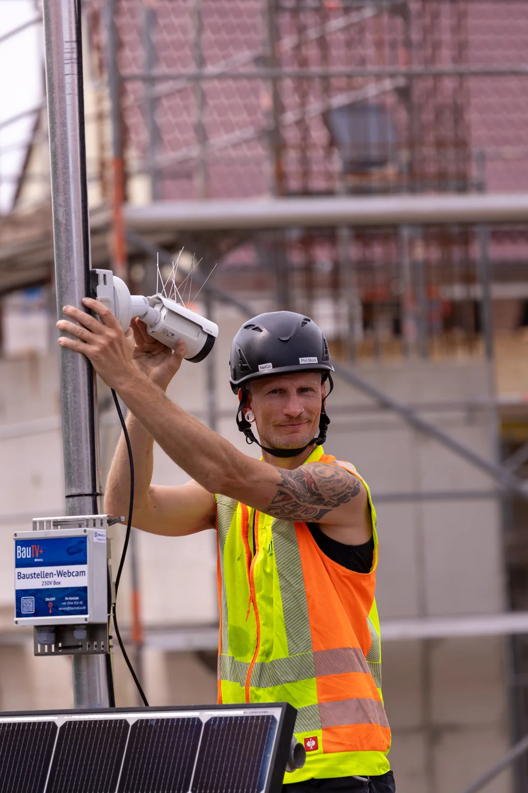 BauTV+ technician installing a construction site camera on a mast